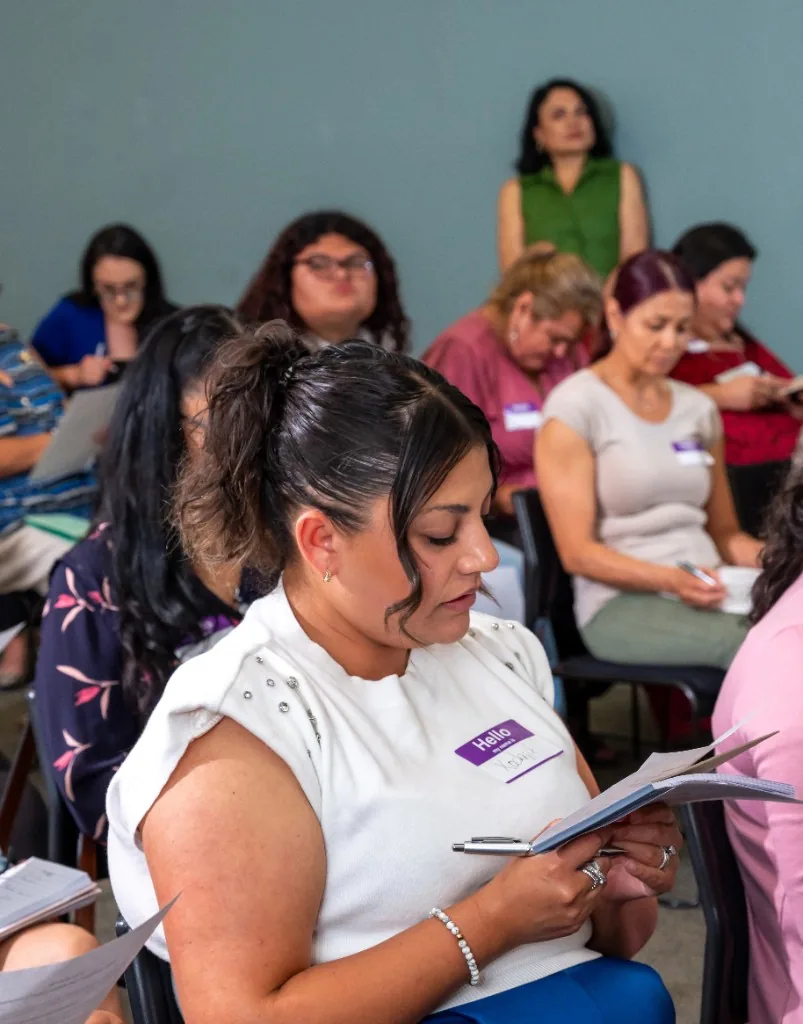 Woman from the La Belleza Nos Une community taking notes during a workshop